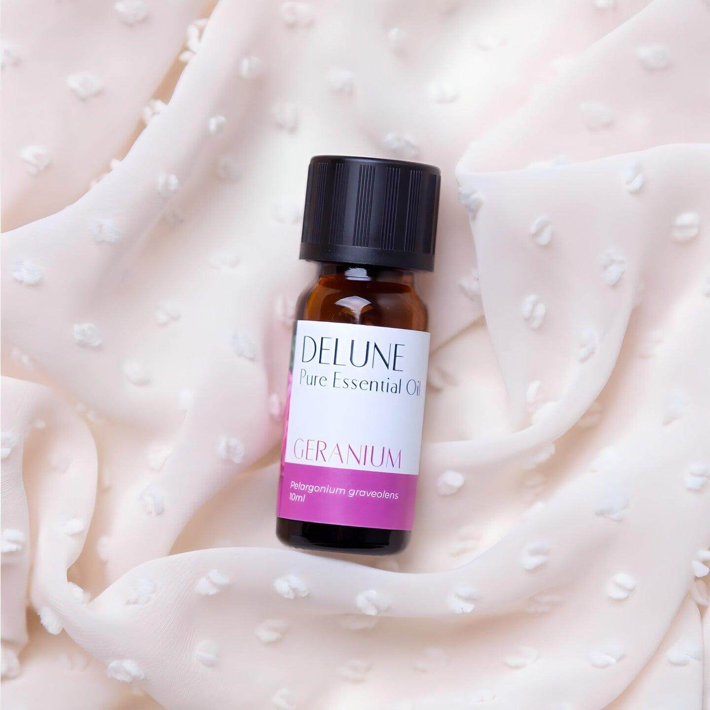 Geranium Pure Essential Oil bottle on soft fabric background, promoting emotional wellness and healthy skin with a sweet floral aroma.