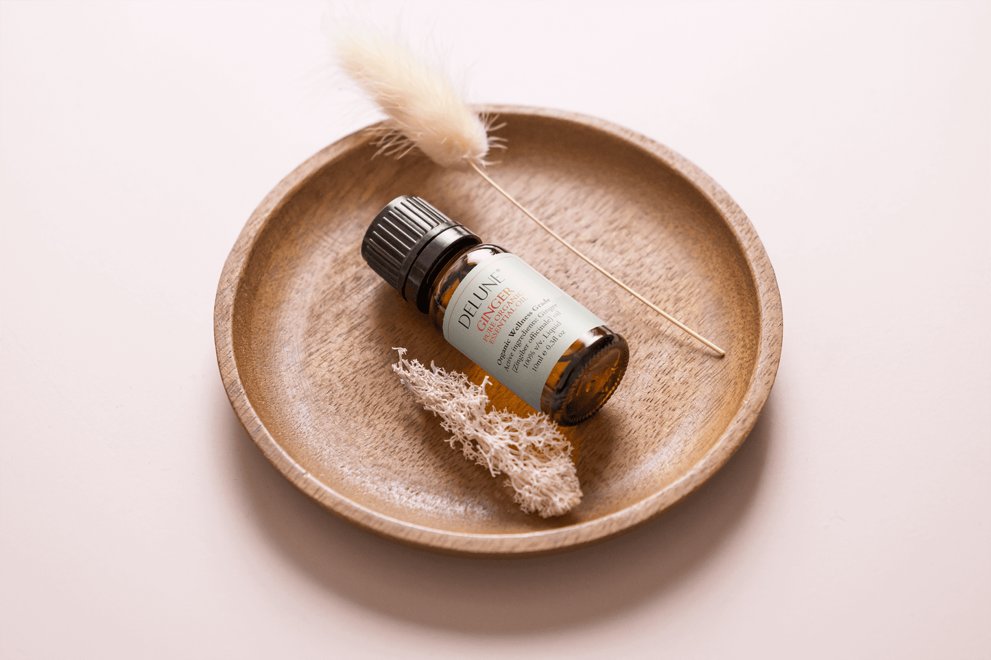 Bottle of Ginger Organic Wellness Grade Essential Oil on a wooden plate with decorative elements, enhancing vitality and energy.