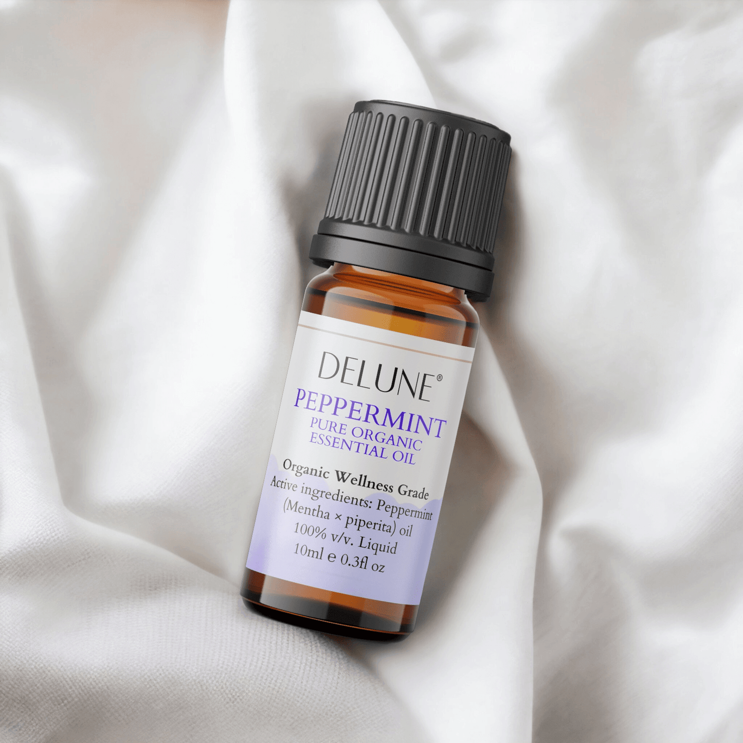 Peppermint Organic Wellness Grade Essential Oil bottle with label, resting on soft fabric, promoting alertness and vitality.