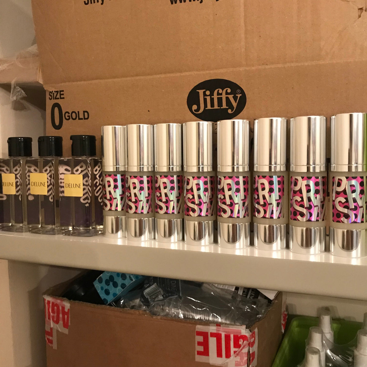 Early Delune roll-on bottles lined up on a shelf in front of shipping boxes