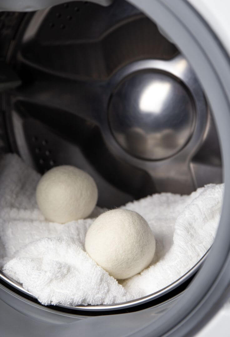 Eco-friendly organic wool dryer balls in a washing machine with towels, promoting natural fabric softening and reduced static.