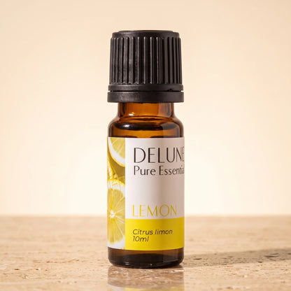 Delune Lemon Pure Essential Oil, 10ml amber glass bottle on warm travertine stone