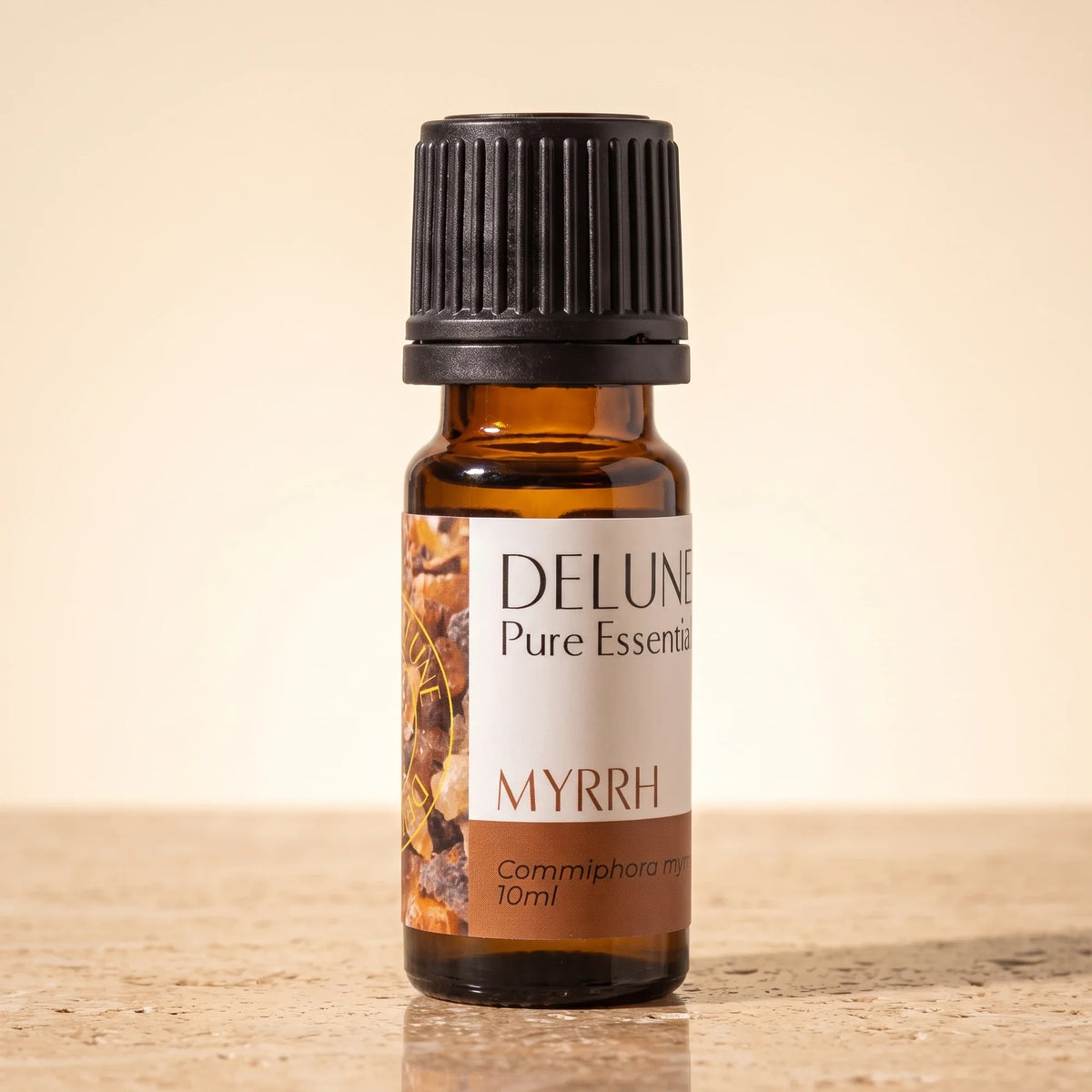 Delune Myrrh Pure Essential Oil, 10ml amber glass bottle on warm travertine stone