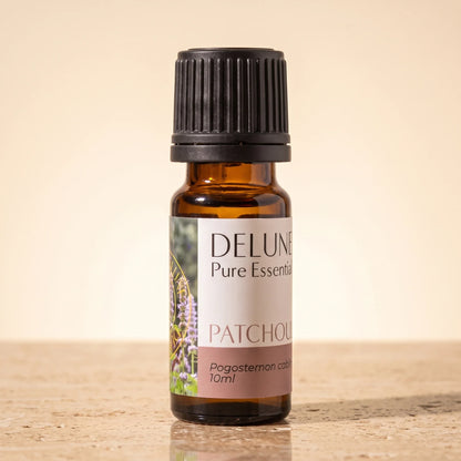 Delune Patchouli Pure Essential Oil, 10ml amber glass bottle on warm travertine stone