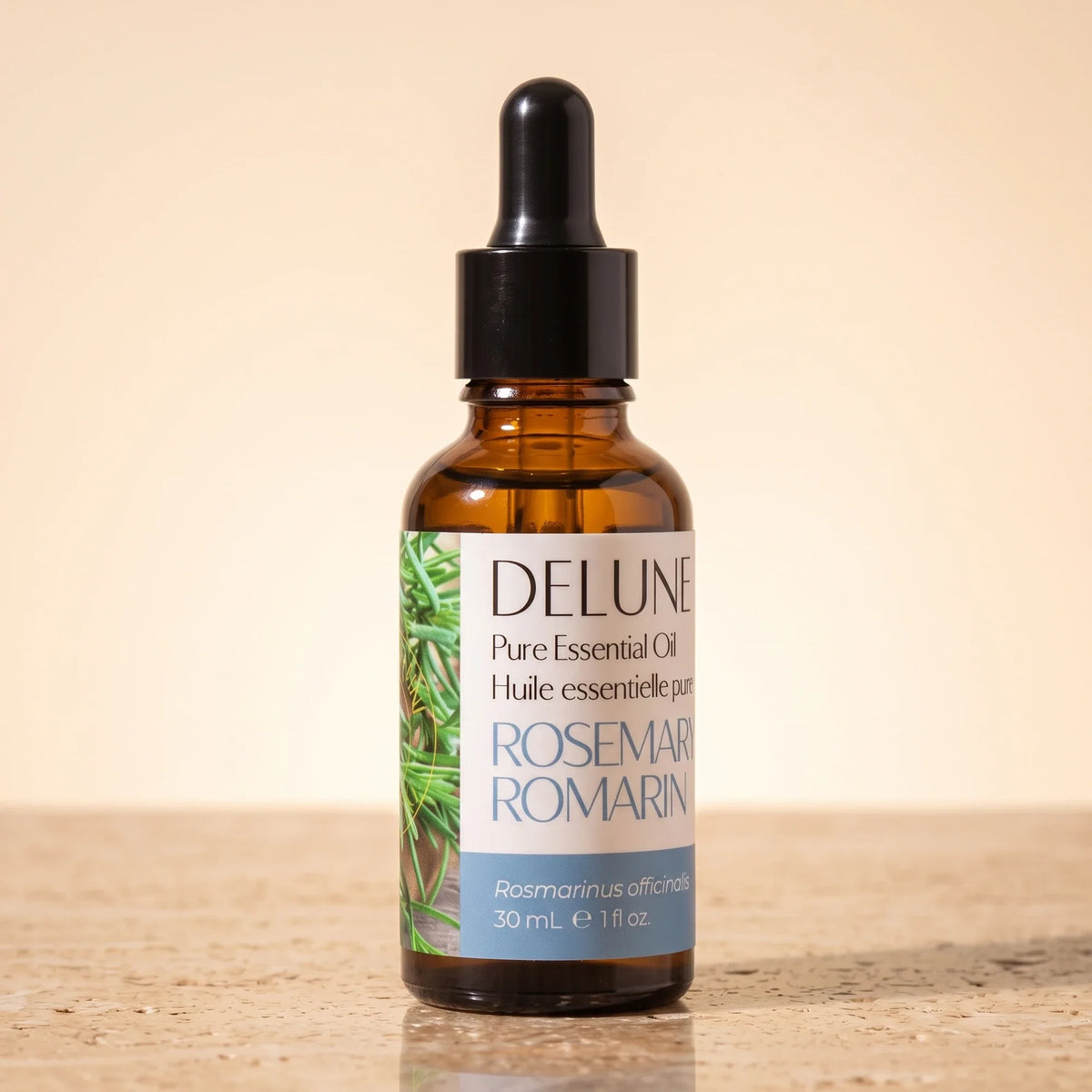 Delune Rosemary Pure Essential Oil, 30ml amber glass dropper bottle on warm travertine stone