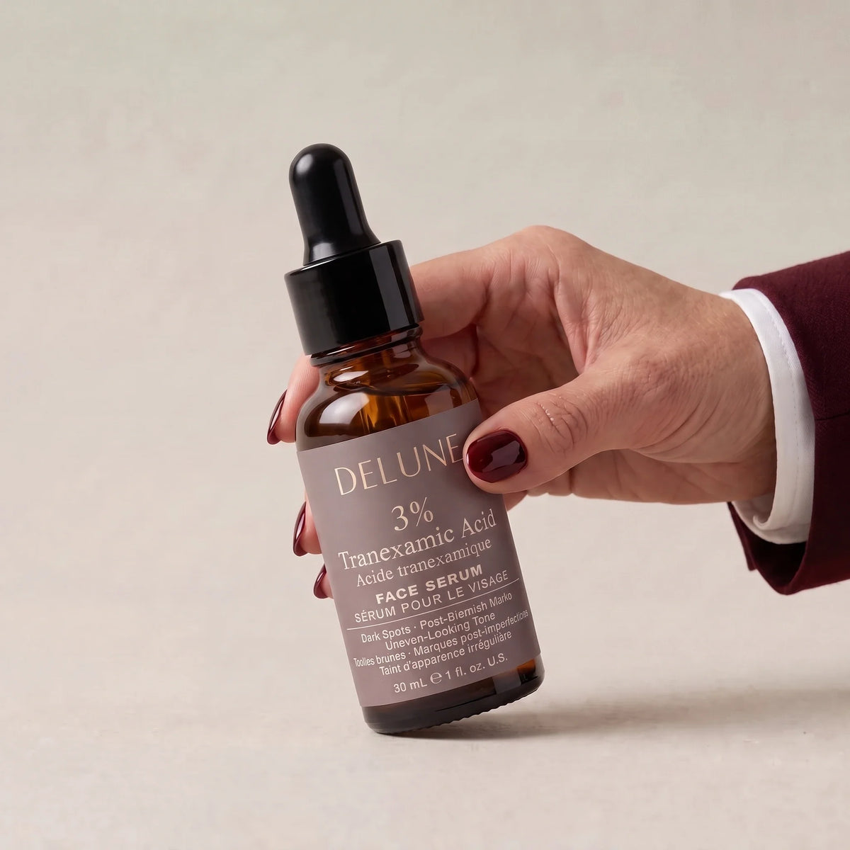 Hand picking up Delune Tranexamic Acid Serum