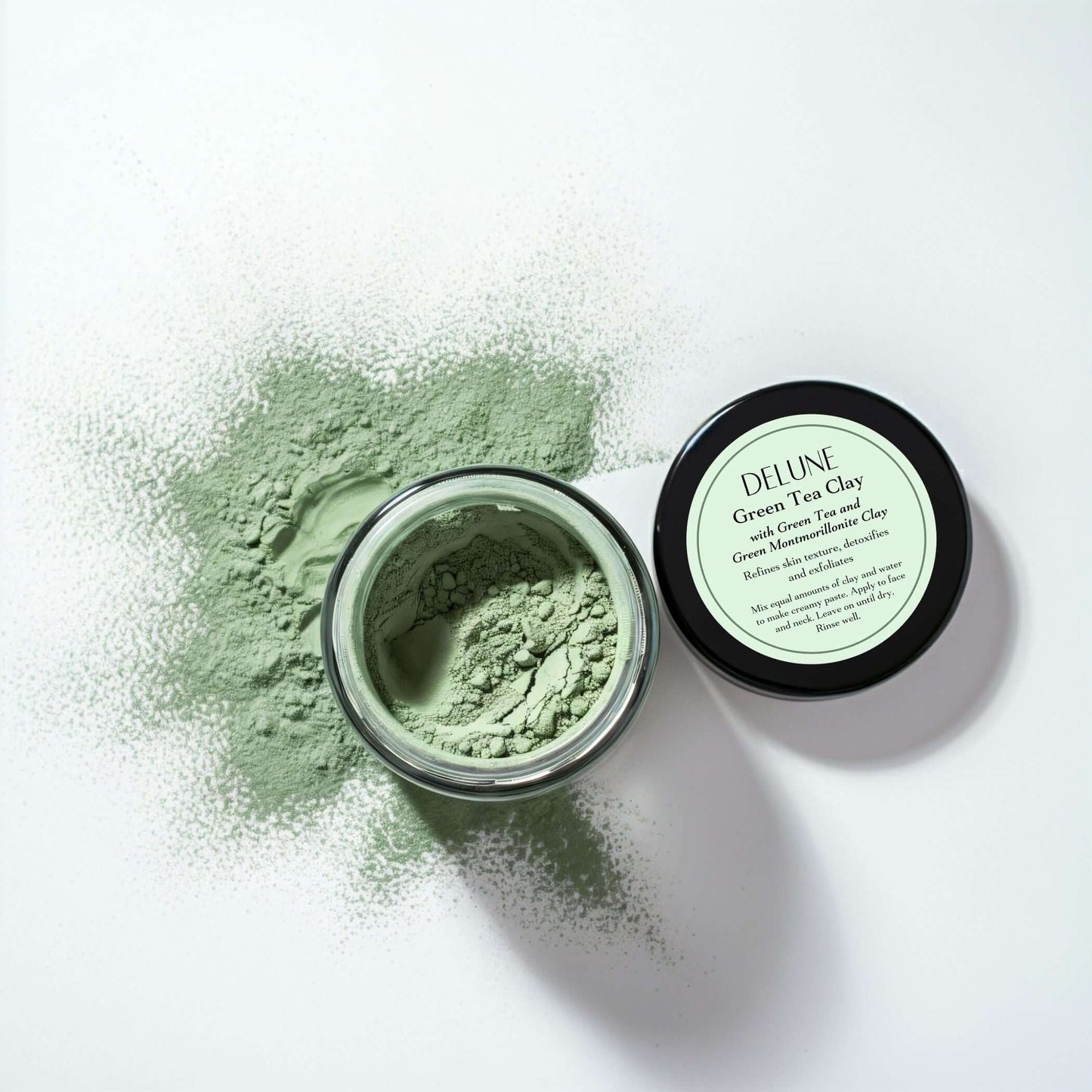 Open jar of Green Tea Clay Mask with scattered green powder, highlighting skin purifying treatment with Matcha and Montmorillonite clay.
