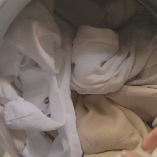 Placing organic wool dryer balls into a laundry machine filled with clothes.