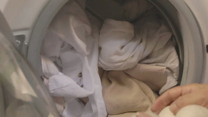 Placing organic wool dryer balls into a laundry machine filled with clothes.