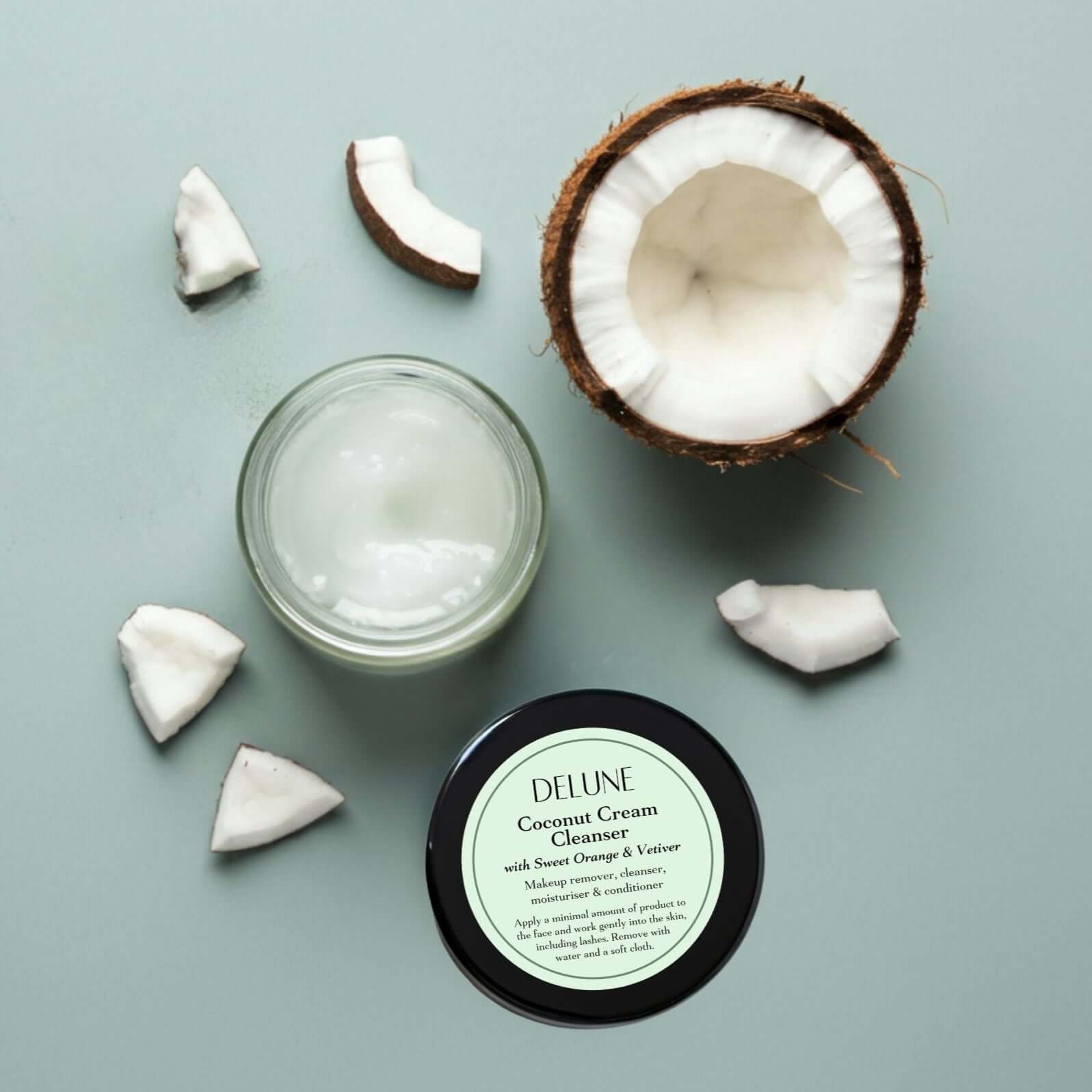 Raw Coconut Cream Cleanser with sweet orange and vetiver scent, nourishing and effective for makeup removal, shown with coconut slices.
